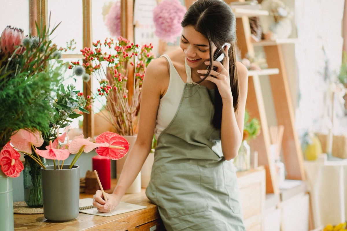 A florist answering a message on her phone in her shop